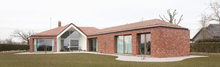 Brick accents are applied to the square columns and surrounding the perimeter of the house up to the middle height of the windows